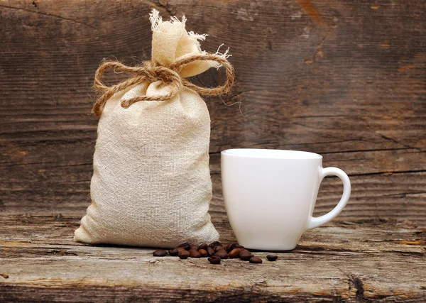 Coffee beans and burlap sack on wooden background — Stock Photo, Image