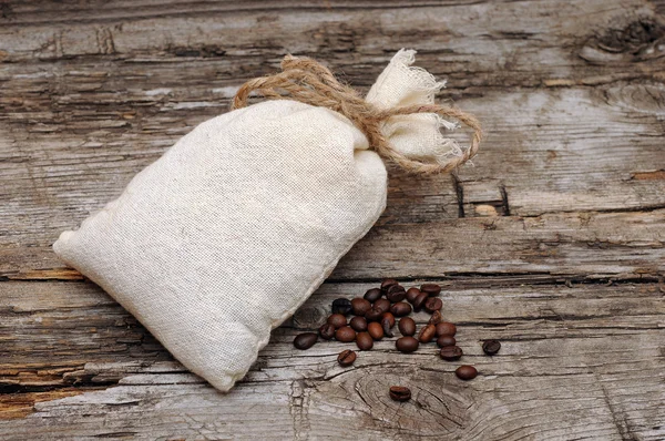 Coffee beans and burlap sack on wooden background — Stock Photo, Image