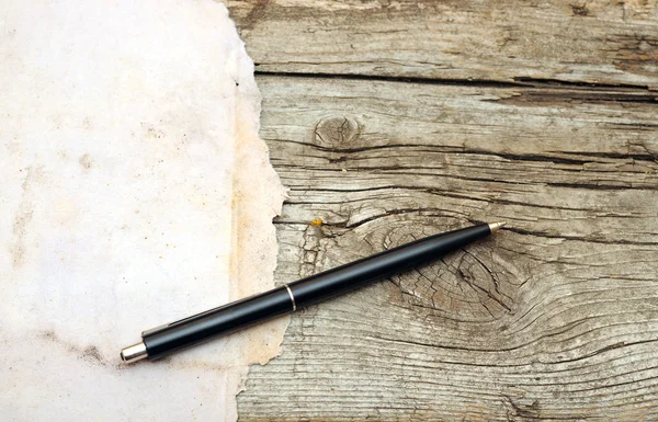 Pen on old paper over old wood table — Stock Photo, Image