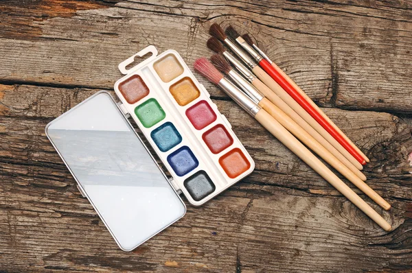 Farben und Pinsel auf altem Holztisch — Stockfoto