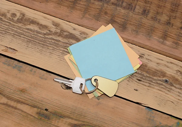 Бумага для заметок и домашние ключи с пустым тегом на деревянном фоне — стоковое фото