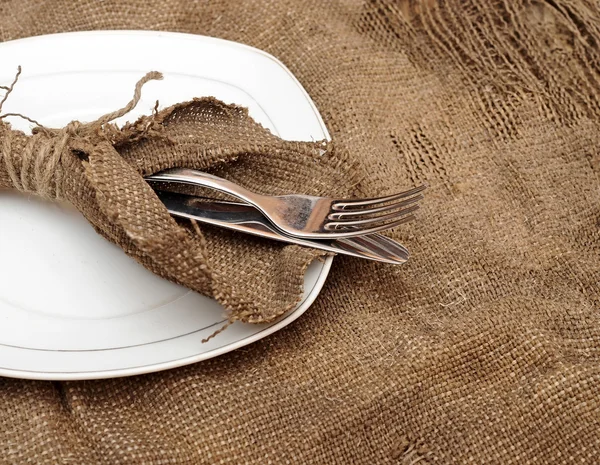 Un posto che mette piatto vuoto, forchetta d'argento e coltello sul vecchio sacco — Foto Stock