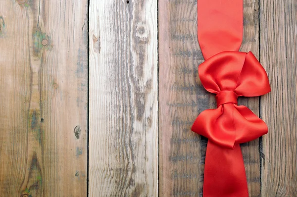 Red bow and ribbon on the old wooden background — Stock Photo, Image