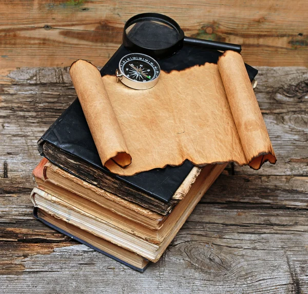 Стопка антикварных книг с компасом, лупой и бумагой — стоковое фото