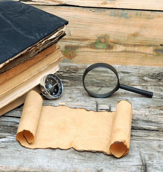 Stack of antique books with compass, magnifying glass and paper — Stock Photo, Image