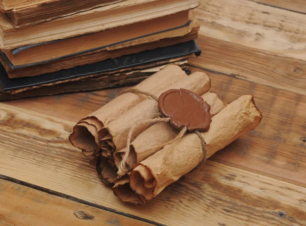 Montón de libros antiguos y pergamino sobre fondo de madera — Foto de Stock