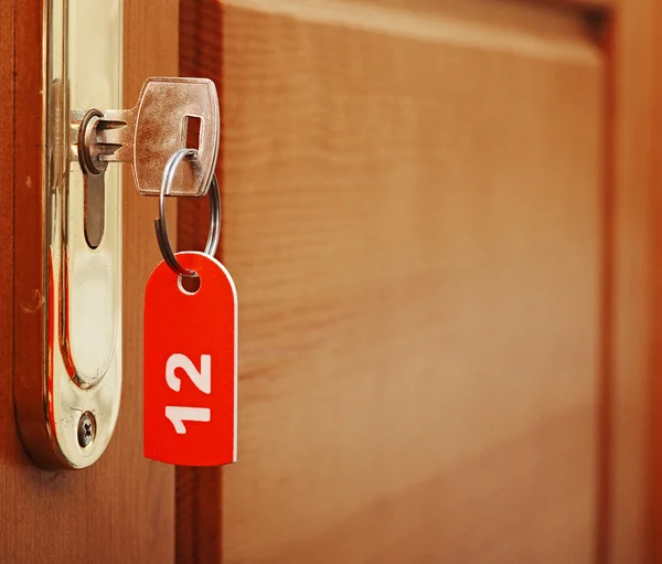 Maçanetas da porta na asa de madeira da porta e chave no buraco da fechadura com número — Fotografia de Stock