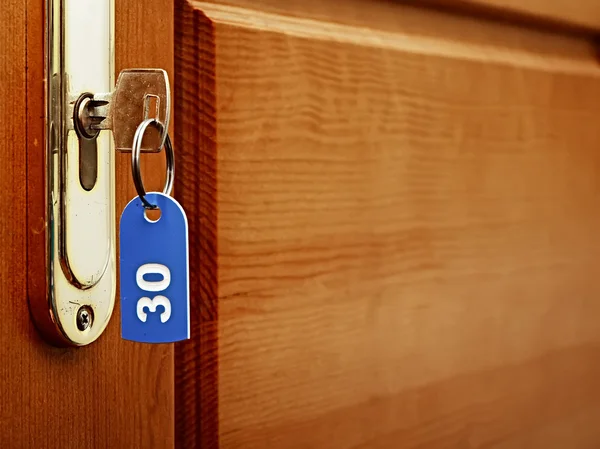 Puerta de madera y llave en cerradura con etiqueta numerada —  Fotos de Stock