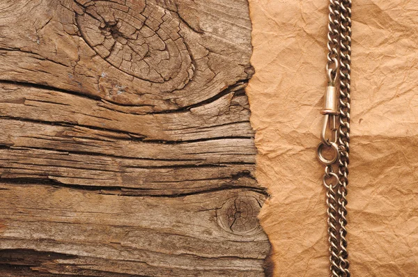 Papel velho com corrente de prata na borda fundo de madeira — Fotografia de Stock