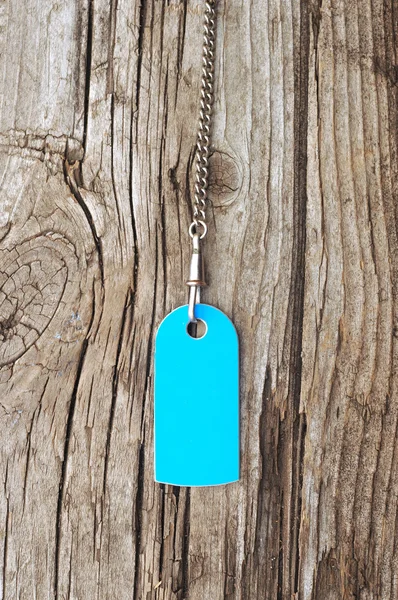Étiquette bleue vierge avec chaîne argentée vieux fond en bois — Photo