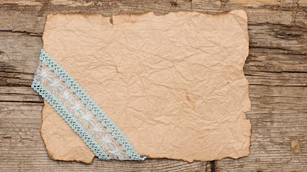 Old paper with beautiful ribbon on brown wood texture — Stock Photo, Image