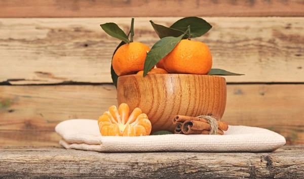 Zimt und Mandarinen mit Blättern auf Holztisch — Stockfoto