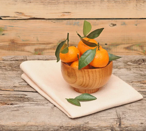 Bowl of fresh mandarins with leaf on wooden table — Stock Photo, Image