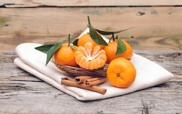 Zimt und Mandarinen mit Blättern in einem schönen Korb, auf dem — Stockfoto