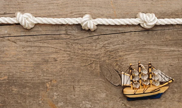 Rope and model classic boat on wood background — Stock Photo, Image