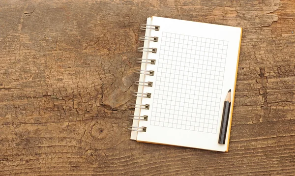 Un cuaderno blanco con lápiz sobre un escritorio de madera — Foto de Stock