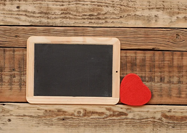 Small blackboard with a red heart on wooden wall — Stock Photo, Image