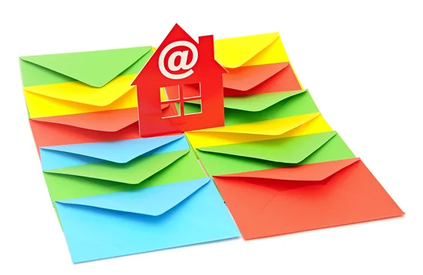 Red plastic house shaped object on colorful envelopes white back — Stock Photo, Image