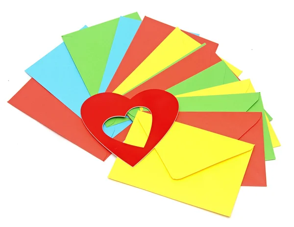 A red heart on pile colorful envelopes over white background — Stock Photo, Image