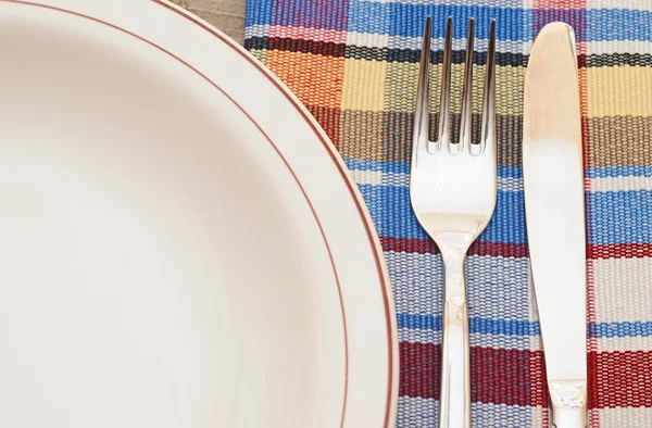 Cadre de table avec fourchette, couteau, assiettes et serviette colorée — Photo