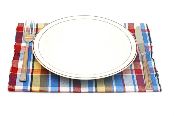 Белая тарелка, нож и вилка на салфетке — стоковое фото