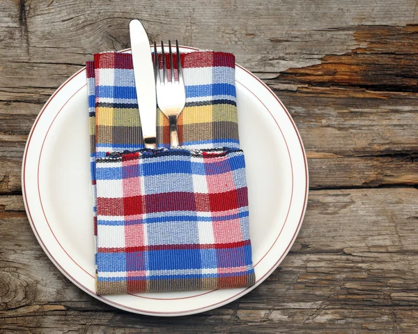 Assiette blanche, couteau et fourchette sur table en bois — Photo