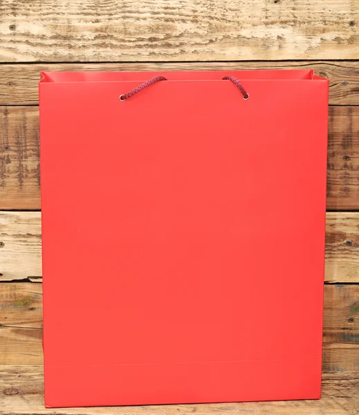 Saco de compras vermelho na parede de madeira — Fotografia de Stock