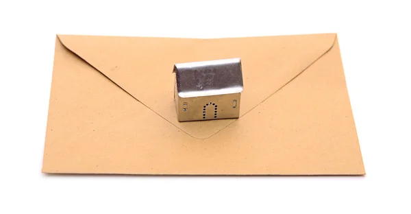 Metall house shaped object on brown envelope — Stock Photo, Image