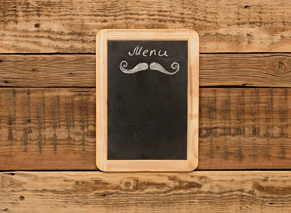Aged menu blackboard hanging on wooden wall — Stock Photo, Image