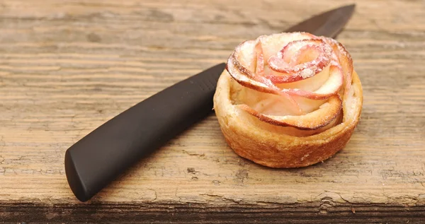Pasteles de manzana como flor con cuchillo en una vieja mesa de cocina . —  Fotos de Stock