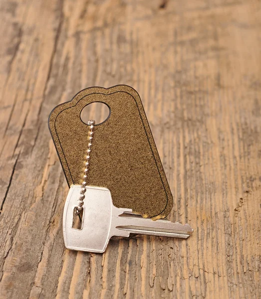 Llave de plata con etiqueta en blanco fondo de madera. espacio para su texto — Foto de Stock