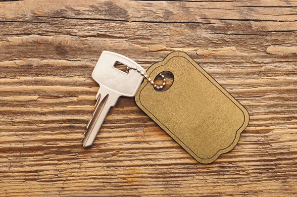 Kunci perak dengan tag kosong latar belakang kayu. spasi untuk teks Anda — Stok Foto