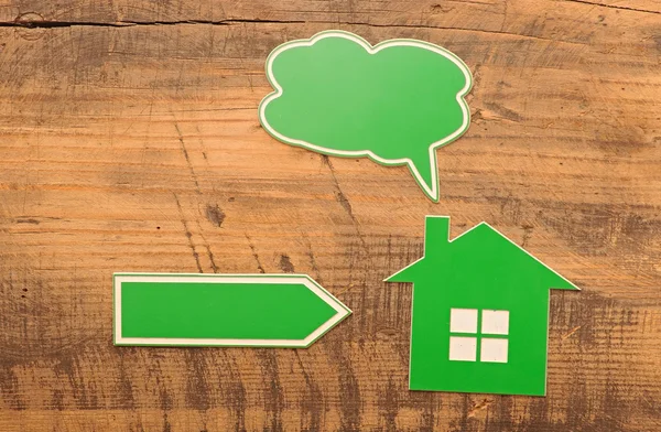 Home icon with blank bubble speech and arrow over wooden backgro — Stock Photo, Image