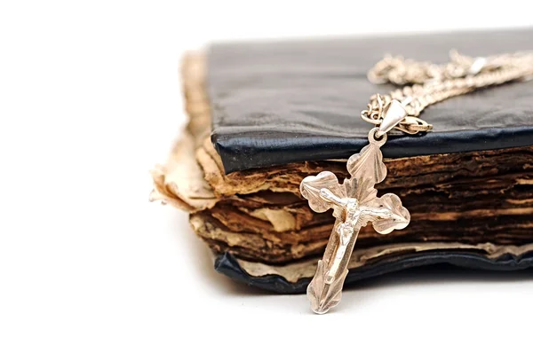 Religie. een kruis met een keten tegen een oud boek — Stockfoto