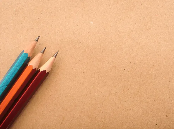 Bunte Bleistifte auf braunem Packpapier Hintergrund, Kartonnotiz — Stockfoto