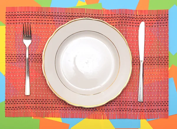 White plate, knife and fork at napkin on colorful background — Stock Photo, Image