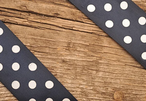 Wooden background with black polka-dot ribbon — Stock Photo, Image