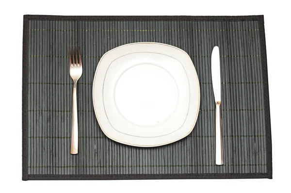 Placemat de bambu com garfo placa e faca isolada em branco — Fotografia de Stock