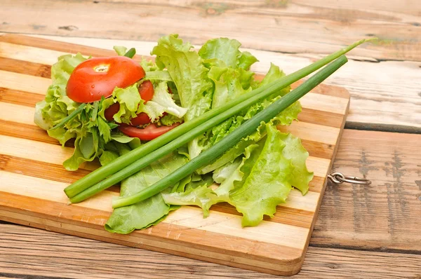 Tomate rojo fresco, cebolla verde, lechuga, perejil, contra una madera —  Fotos de Stock