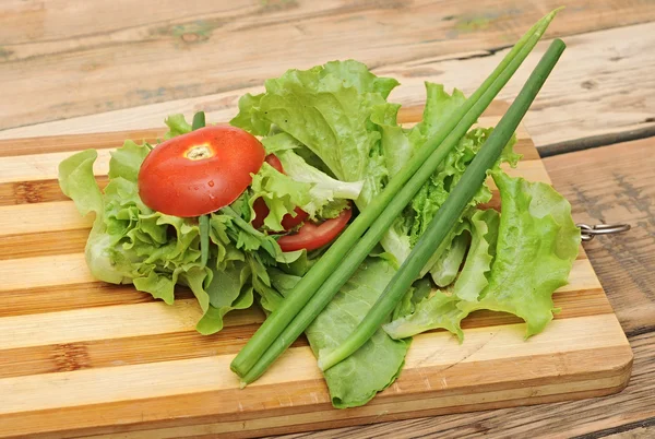 Tomate rojo fresco, cebolla verde, lechuga, perejil, contra una madera —  Fotos de Stock