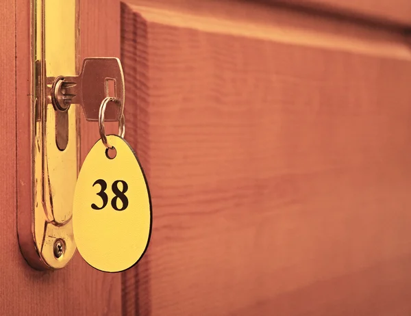 Дверные ручки на деревянном крыле двери и ключ в замочной скважине с номером — стоковое фото
