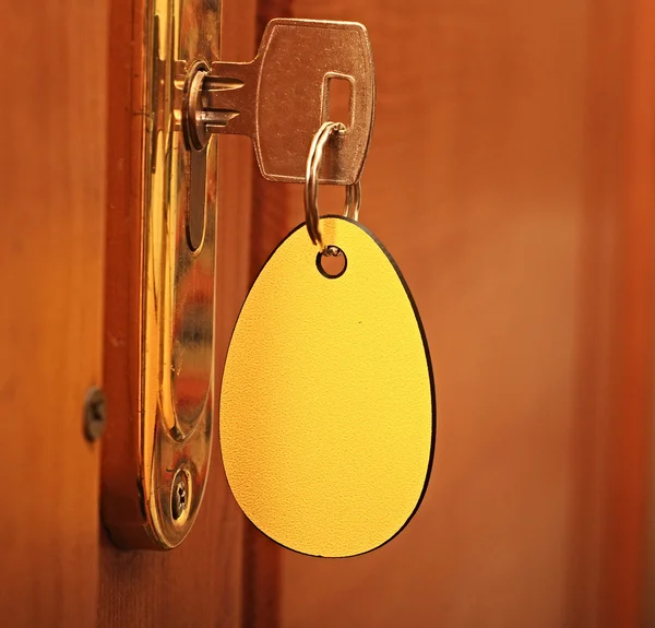 Key in keyhole with blank label — Stock Photo, Image