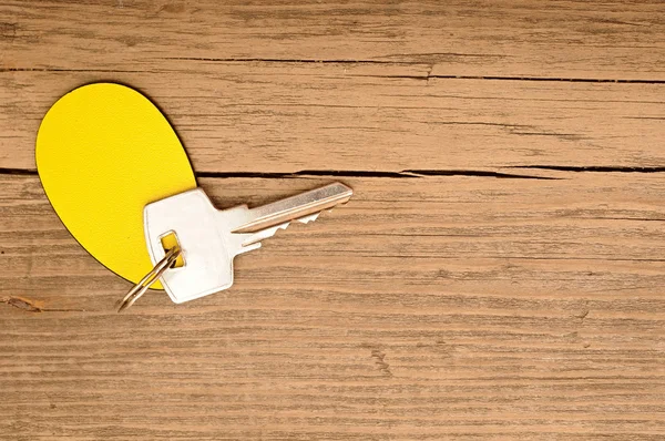 Etiqueta en blanco y una llave sobre fondo de madera — Foto de Stock