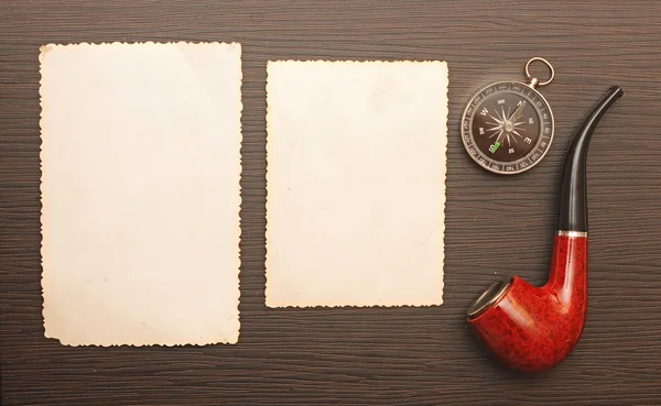 Compass and a pipe with a old photo frame on wooden background — Stock Photo, Image