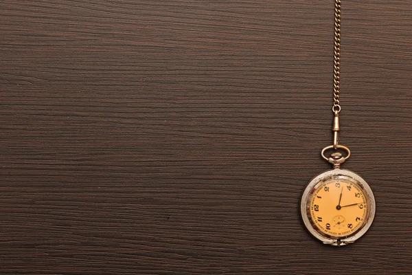 Foto de reloj de bolsillo vintage de plata con cadena en respaldo de madera —  Fotos de Stock