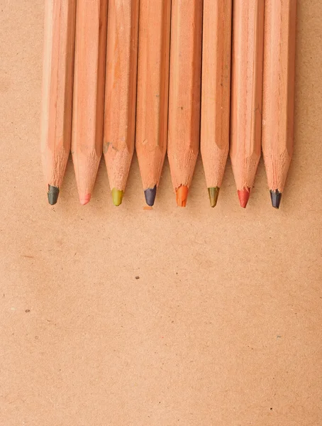 Colorful pencils on brown packing paper background, carton noteb — Stock Photo, Image