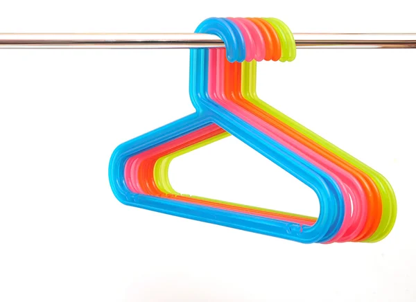 Colorful plastic hangers hanging on a rod over white background — Stock Photo, Image