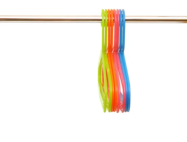 Colorful plastic hangers hanging on a rod over white background — Stock Photo, Image