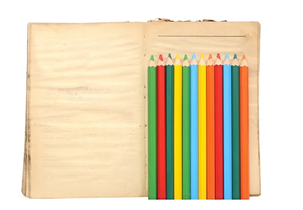 Lápis de cor de madeira e livro velho sobre fundo branco — Fotografia de Stock