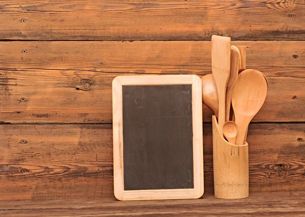 Blank blackboard on wooden surface and wooden utensils — Stock Photo, Image